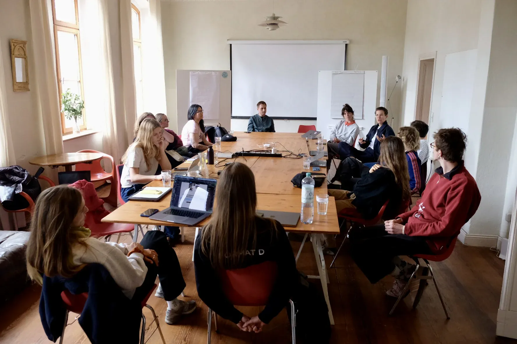 Einige Menschen sitzen an einem langen Konferenztisch und besprechen ein Thema
