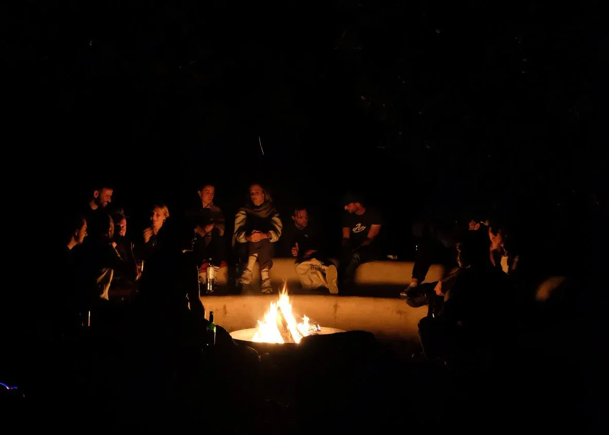 Abends sitzen Menschen rund um ein Lagerfeuer