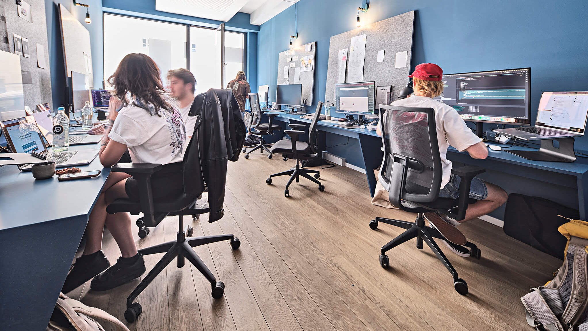 Team sitzt an Monitoren zusammen und arbeitet an barrierefreien Webseiten