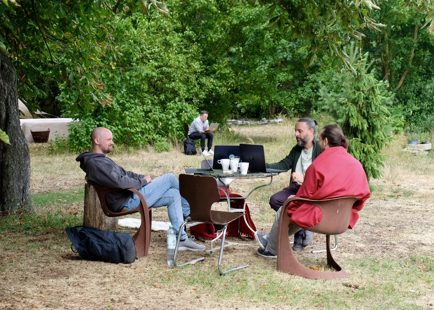 Drei Personen sitzen im Garten und unterhalten sich