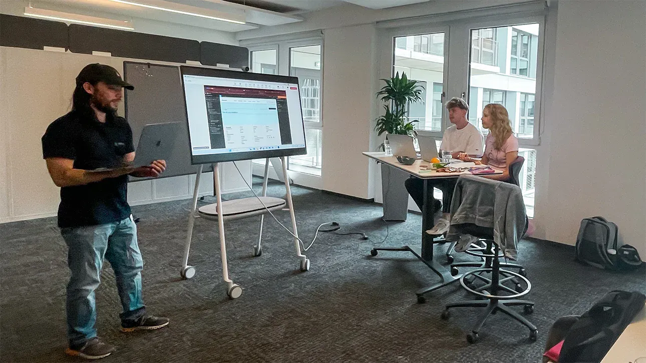 2 personen sehen einer person bei einer präsentation zu in einem bürogebäude