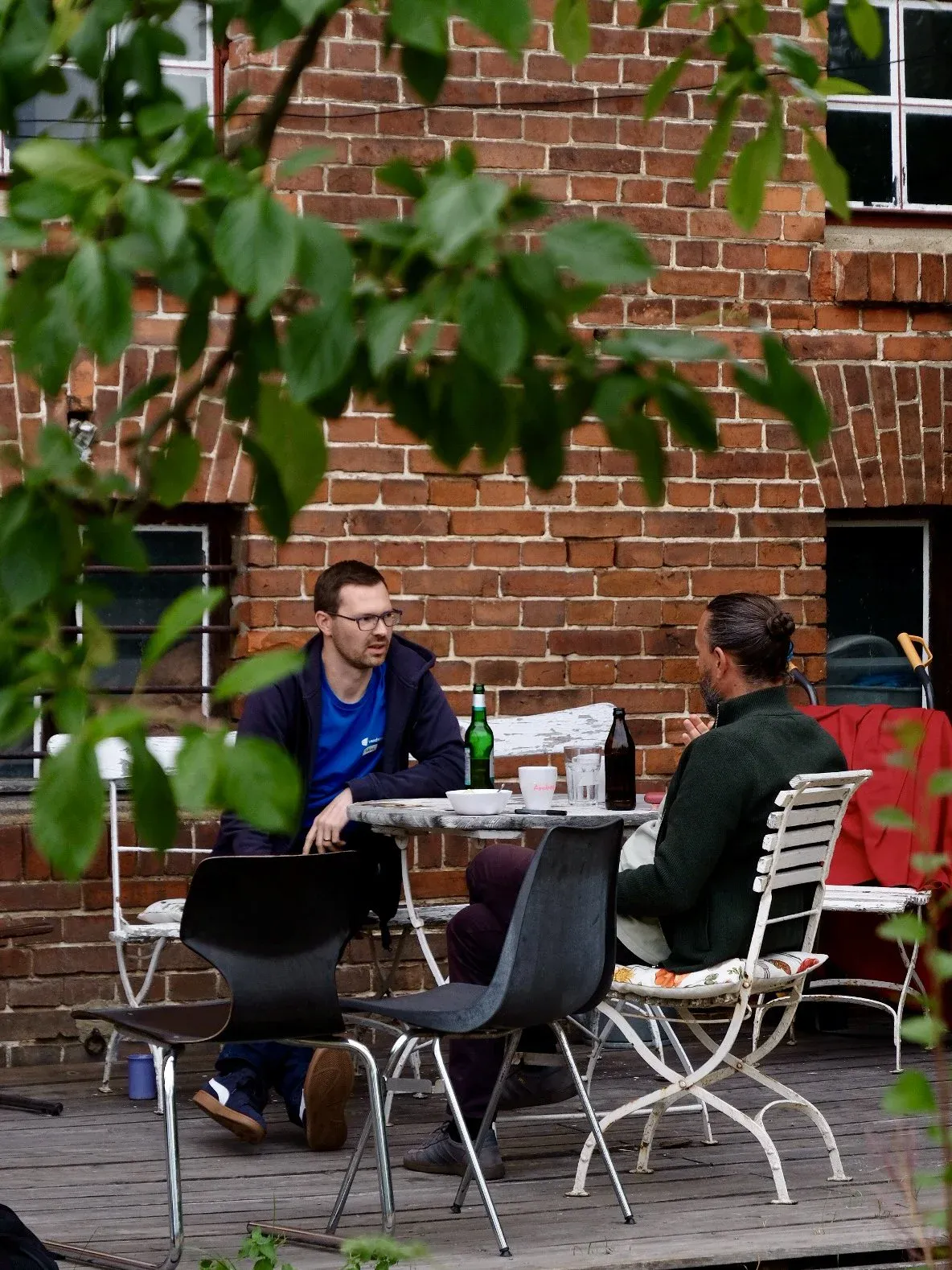 Zwei Personen sitzen auf der Terasse vor dem Haus und unterhalten sich