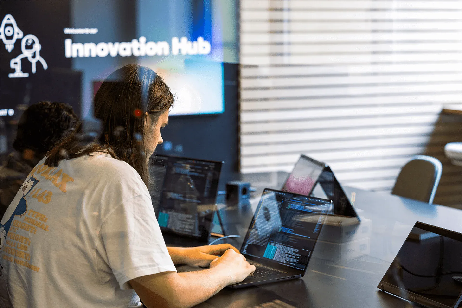 Mann sitzt an einem Tisch mit Laptop und programmiert